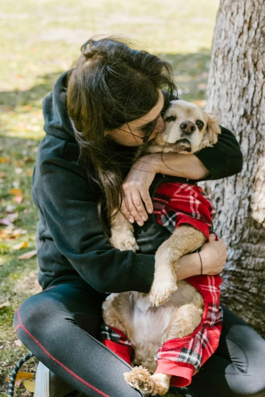 a woman sitting next to a tree hugging a dog, wearing a scarlet hoodie, tear, detailed », bay area