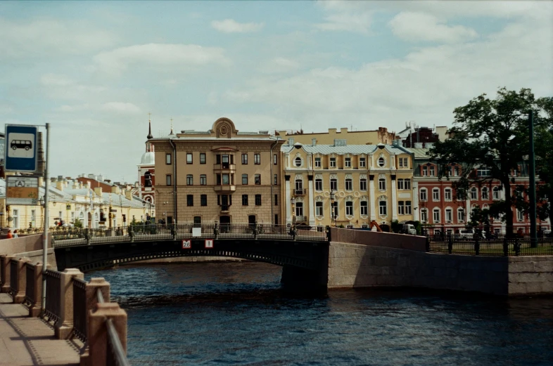 a bridge over a river with buildings in the background, inspired by Vasily Surikov, pexels contest winner, neoclassicism, wes anderson film screenshot, kodak portra 400, saint petersburg, exterior view