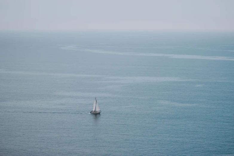 a sailboat in the middle of a large body of water, a picture, by Elsa Bleda, unsplash contest winner, minimalism, blue gray, ignant, muted colours 8 k, secluded