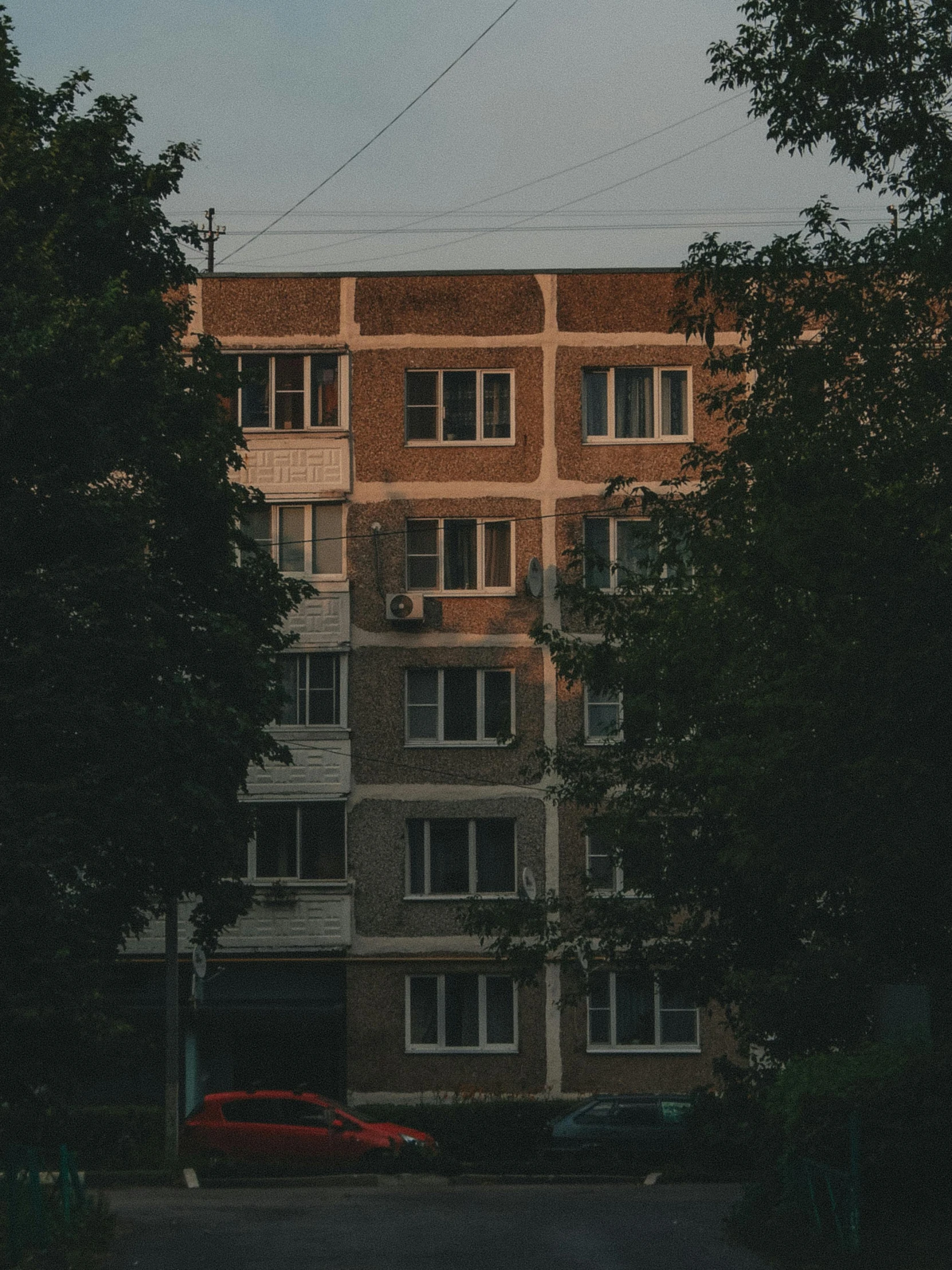 a red car parked in front of a tall building, a photo, inspired by Elsa Bleda, pexels contest winner, soviet suburbs, summer evening, against the backdrop of trees, 000 — википедия