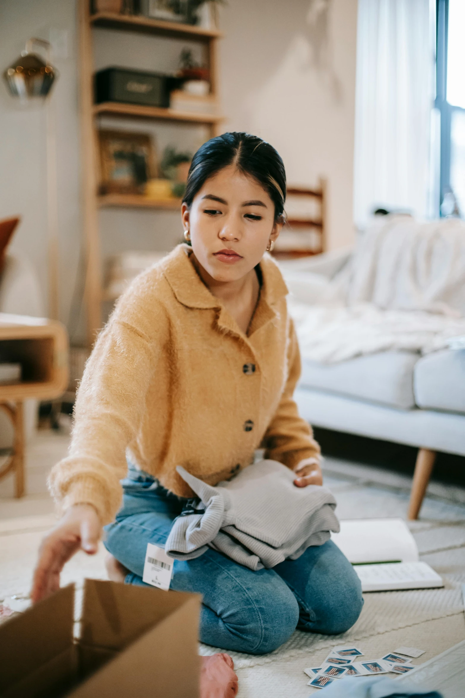 a woman sitting on the floor in front of a box, trending on pexels, with two front pockets, stuffed toy, wearing a turtleneck and jacket, carrying a tray