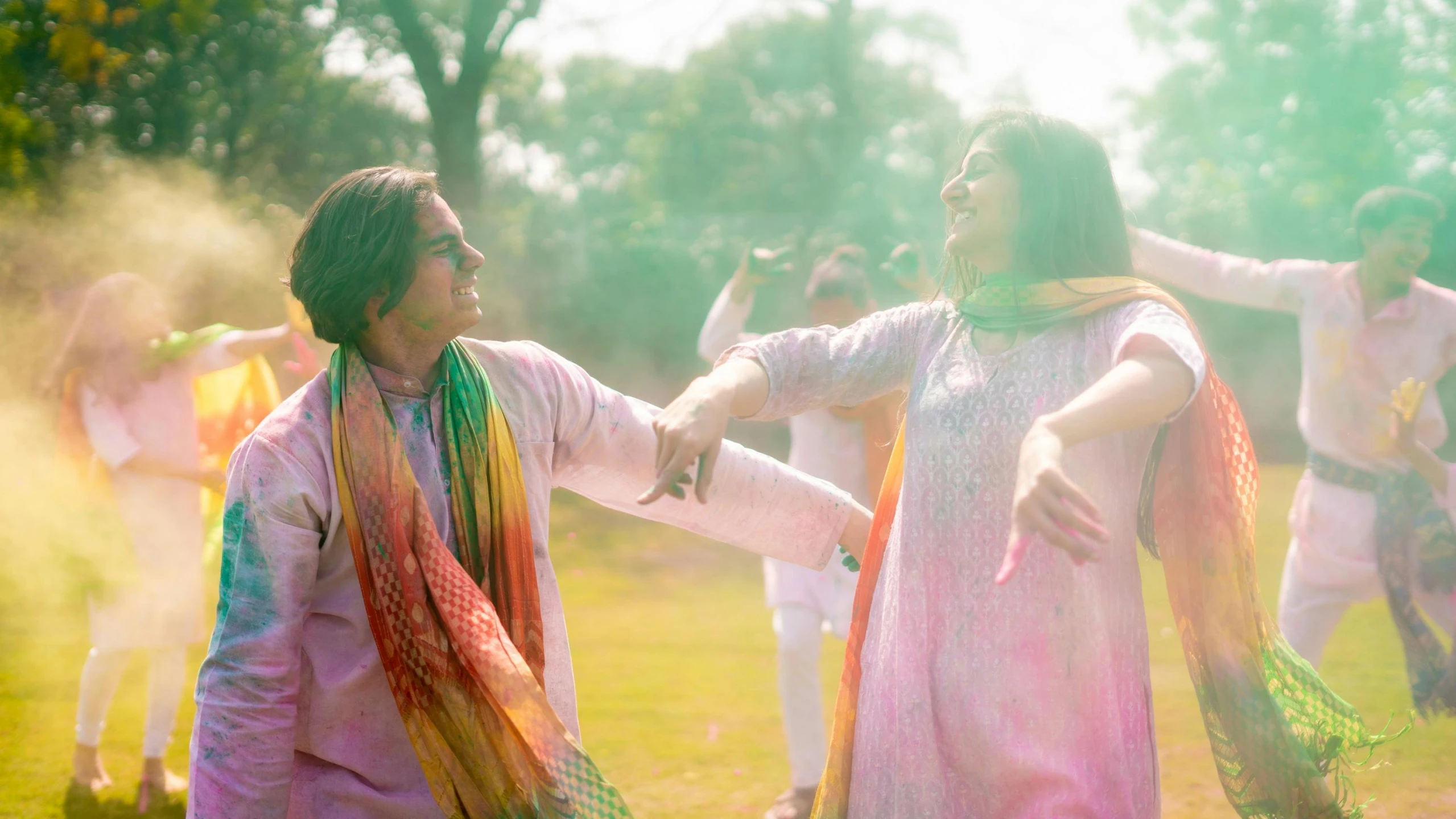 a group of people standing on top of a lush green field, a colorized photo, pexels, color field, wearing a silk kurta, dancing with each other, happy couple, ( ( theatrical ) )