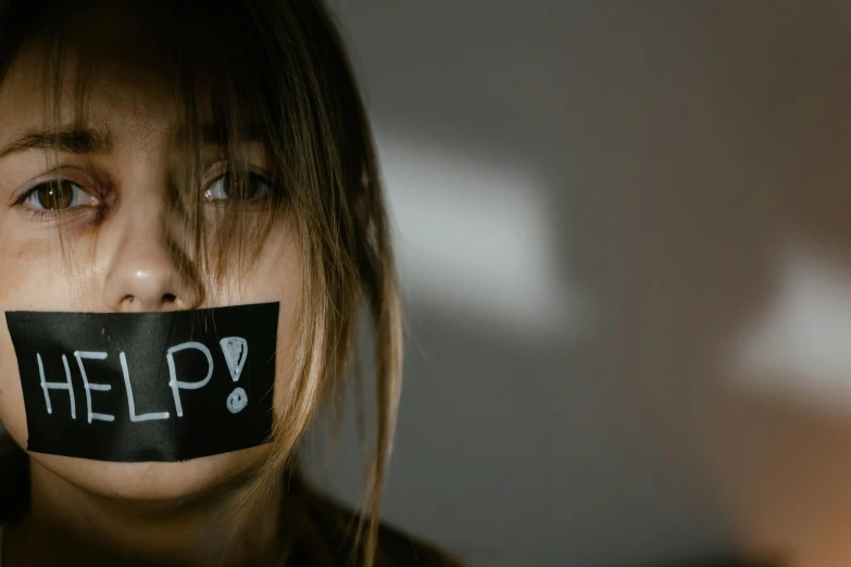 a girl with tape over her mouth that says help, by Adam Marczyński, trending on pexels, black choker, placards, no light, girl with brown hair