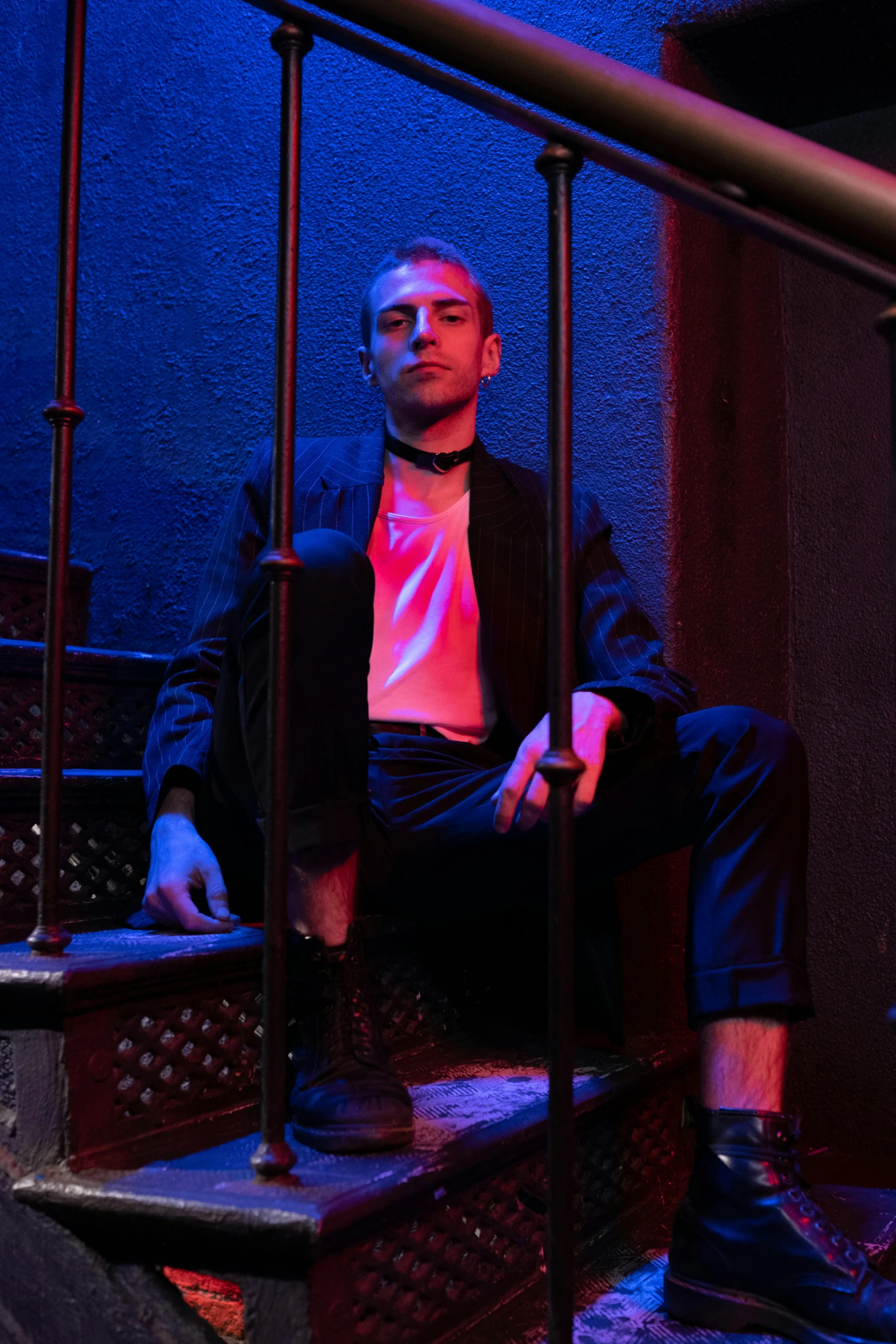 a man sitting on a set of stairs, an album cover, inspired by Nan Goldin, unsplash, renaissance, night clubs and neons, behind bars, extremely handsome, saul better call saul