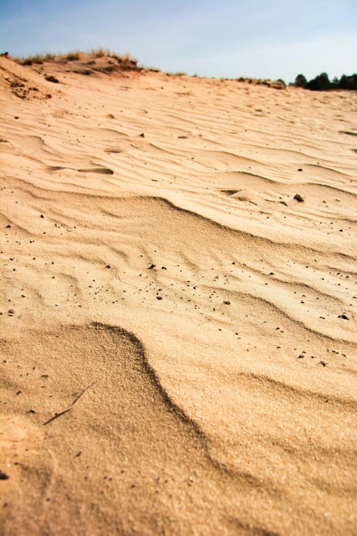 a person riding a surfboard on top of a sandy beach, dry dirt, up-close, at the desert, honey ripples