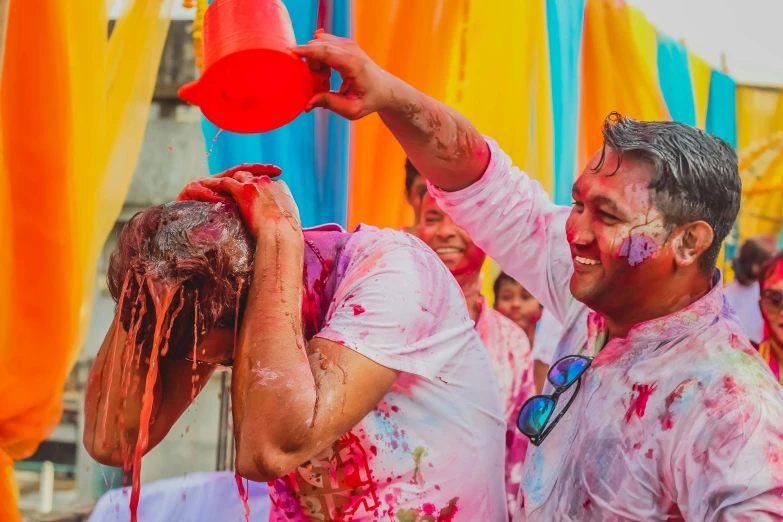 a man holding a bucket on top of a woman's head, pexels contest winner, action painting, festive colors, white limbo, india, gooey skin