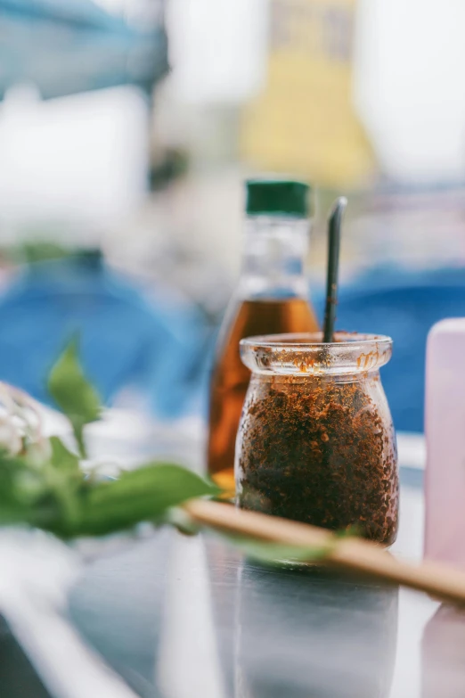 a table topped with bottles of liquid and a wooden spoon, trending on unsplash, ice coffee, luscious patty with sesame seeds, thawan duchanee, overexposed photograph