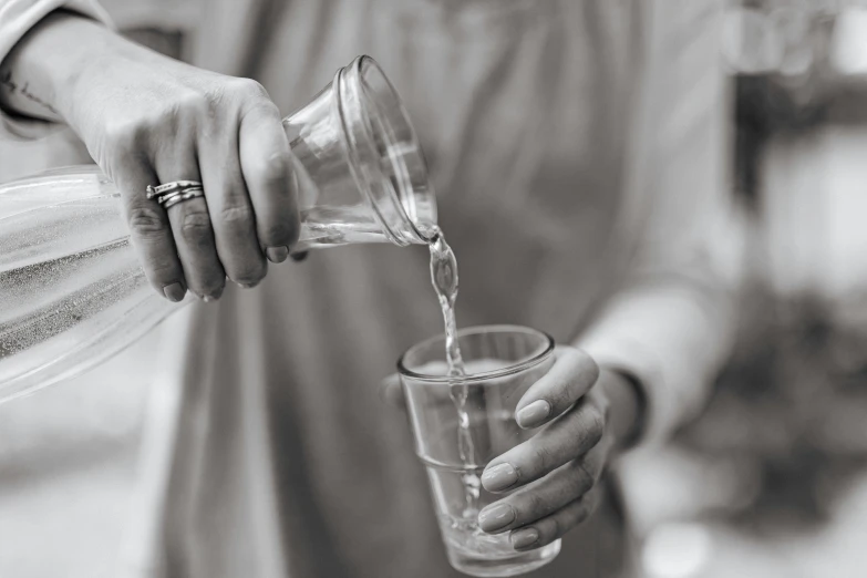 a person pouring water from a pitcher into a glass, a black and white photo, pexels, renaissance, partially cupping her hands, accurate to egyptian tradition, nursing, made of drink