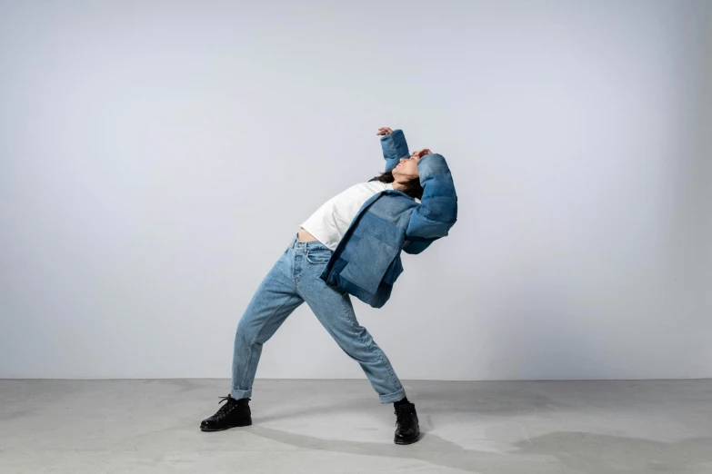 a man in a blue jacket and jeans doing a handstand, by Nina Hamnett, model wears a puffer jacket, pudica pose gesture, rocking out, louise zhang