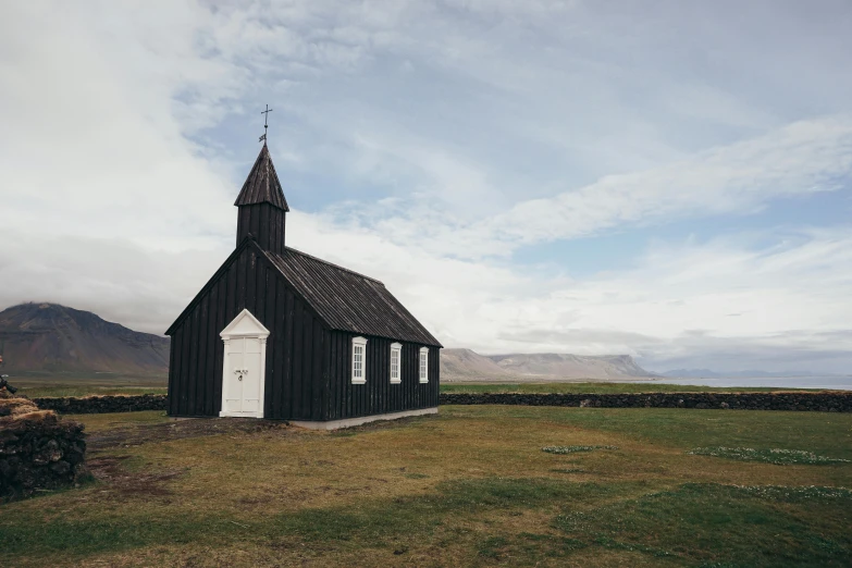 a black church sitting on top of a grass covered field, by Hallsteinn Sigurðsson, unsplash contest winner, renaissance, background image, rustic, but minimalist, 90s photo