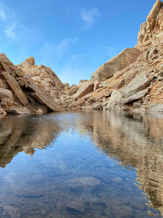 a body of water surrounded by large rocks, reflecting pool, brown canyon background, no surroundings, craggy