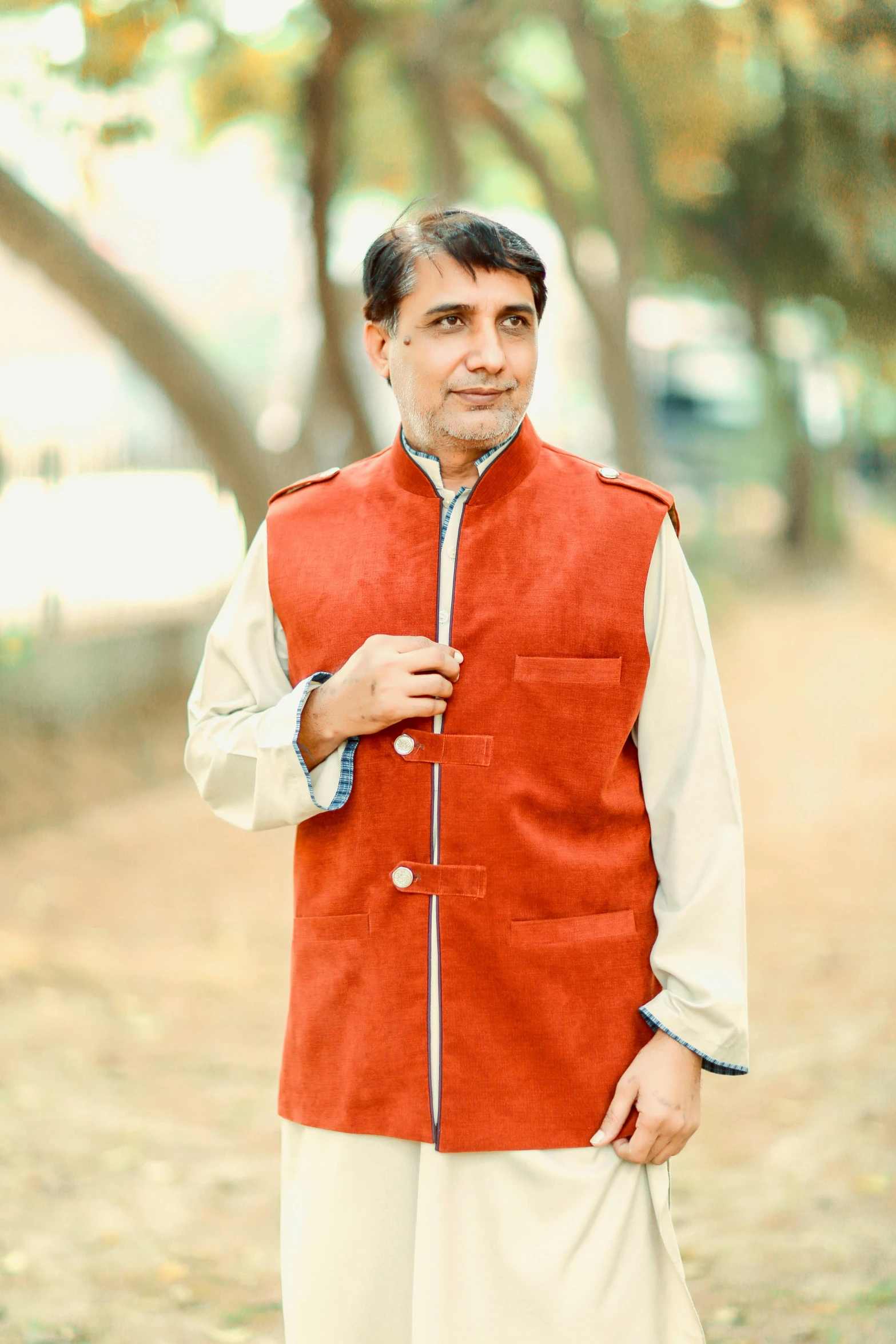 a man in a red vest and white pants, inspired by Sardar Sobha Singh, dark grey and orange colours, promo photo, wearing jacket, corduroy