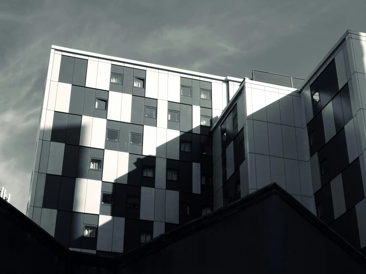 a black and white photo of a building, inspired by Richard Wilson, unsplash, brutalism, evening sun, squares, coventry city centre, hotel room