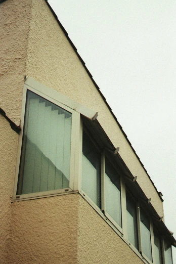 a clock that is on the side of a building, an album cover, inspired by Robert Bechtle, brutalism, rainy; 90's photograph, bay window, very poor quality of photography, pareidolia