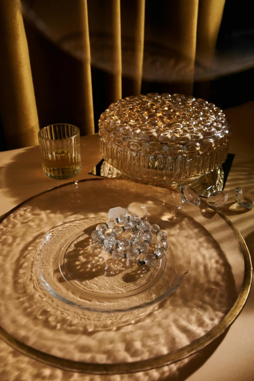 a glass bowl sitting on top of a table, inspired by Marie-Gabrielle Capet, baroque, sparkling crystals, cake, play of light, set pieces