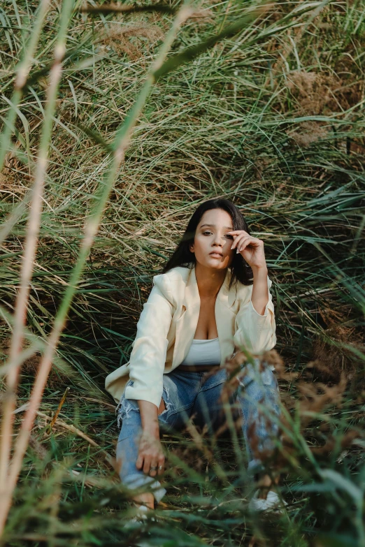 a woman sitting in the grass talking on a cell phone, an album cover, unsplash, portrait demi rose, standing in tall grass, tessa thompson inspired, low quality photo