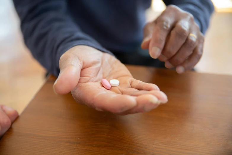 a person holding a pill in their hand, unsplash, photorealism, on a wooden tray, older male, thumbnail, unedited