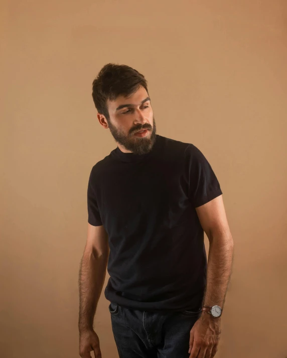 a man with a beard standing in front of a cake, an album cover, by Adam Dario Keel, hurufiyya, wearing a black tshirt, lgbtq, ignant, slightly defined jawline