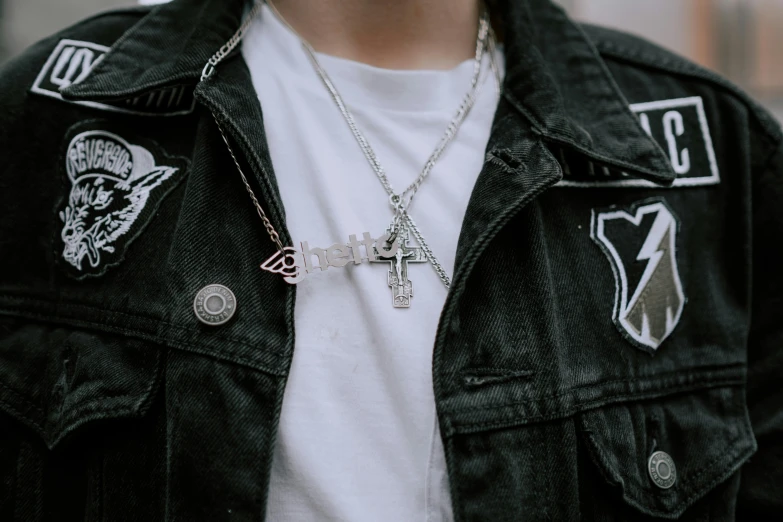 a close up of a person wearing a jacket with a cross on it, trending on pexels, [ metal ], black and silver, offwhite, hot topic