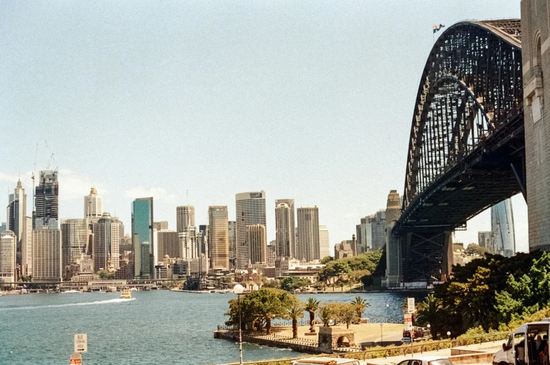 a bridge over a body of water with a city in the background, inspired by Sydney Carline, pexels contest winner, hurufiyya, f 1.4 kodak portra, on a sunny day, 1980s photo, slide show