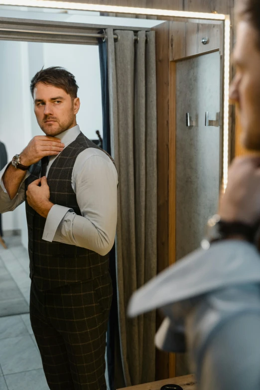 a man adjusting his tie in front of a mirror, inspired by Ramon Pichot, pexels contest winner, happening, model is wearing techtical vest, heath clifford, structure : kyle lambert, exiting from a wardrobe