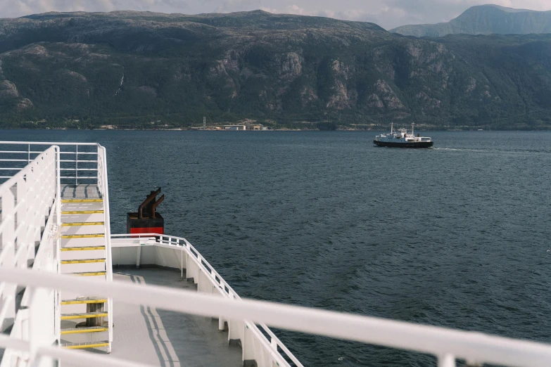 a boat on a body of water with mountains in the background, by Jóhannes Geir Jónsson, happening, standing on ship deck, thumbnail, cinematic image, a high angle shot