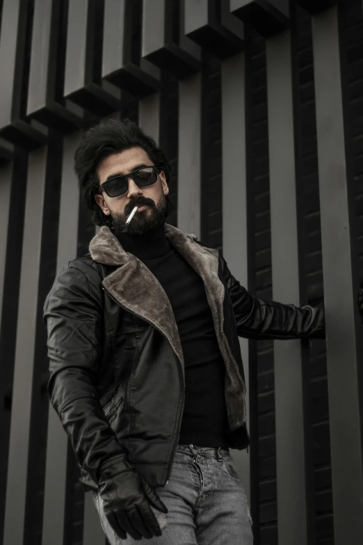 a man standing in front of a building smoking a cigarette, an album cover, by Ismail Acar, pexels contest winner, leather fur jacket, bearded beautiful man, superhero, casual pose