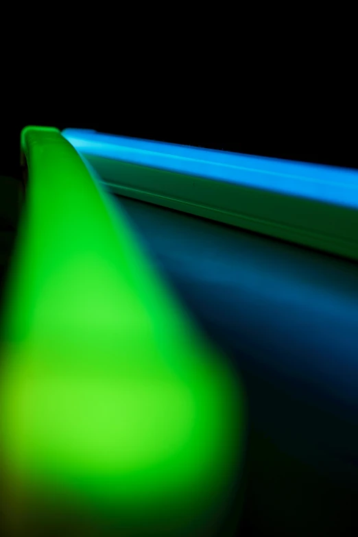 a close up of a toothbrush on a table, by Doug Ohlson, blue and green light, luminescent fabrics, gradient from green to black, neon green