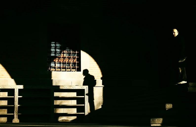 a person sitting on a bench in a dark room, by Giuseppe Camuncoli, romanesque, contre jour, standing astride a gate, instagram picture, crypt