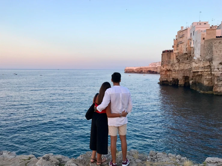 a man and a woman standing on a cliff overlooking the ocean, pexels contest winner, apulia, avatar image, evening, unedited