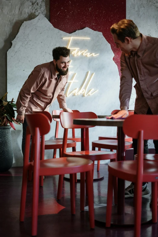 a couple of men standing next to each other at a table, trending on unsplash, happening, red velvet furniture, chairs and tables, carefully designed, plating