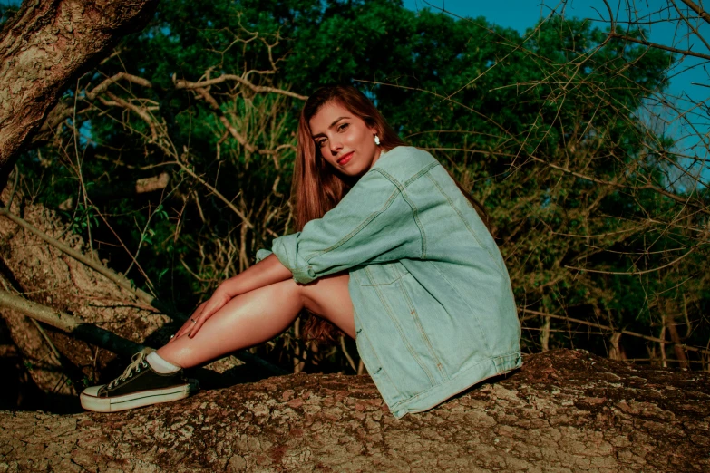 a woman sitting on top of a tree branch, an album cover, inspired by Elsa Bleda, trending on pexels, realism, jean jacket, satisfied pose, green clothes, 15081959 21121991 01012000 4k