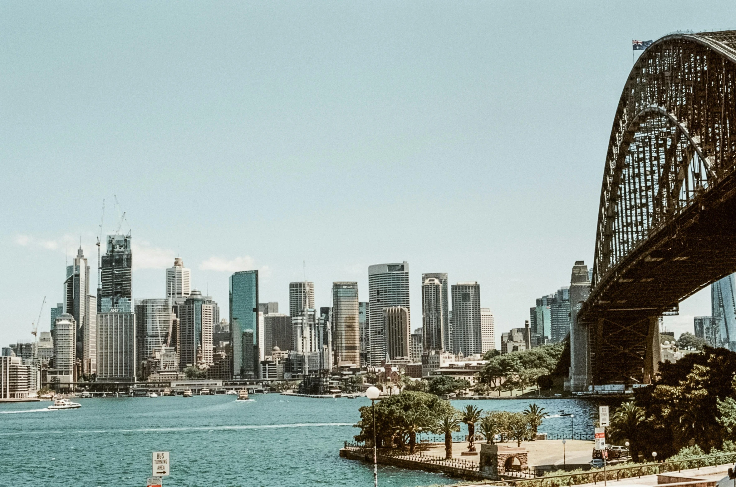 a bridge over a body of water with a city in the background, inspired by Sydney Carline, pexels contest winner, sunny day, unsplash photography, high rise buildings, 2000s photo