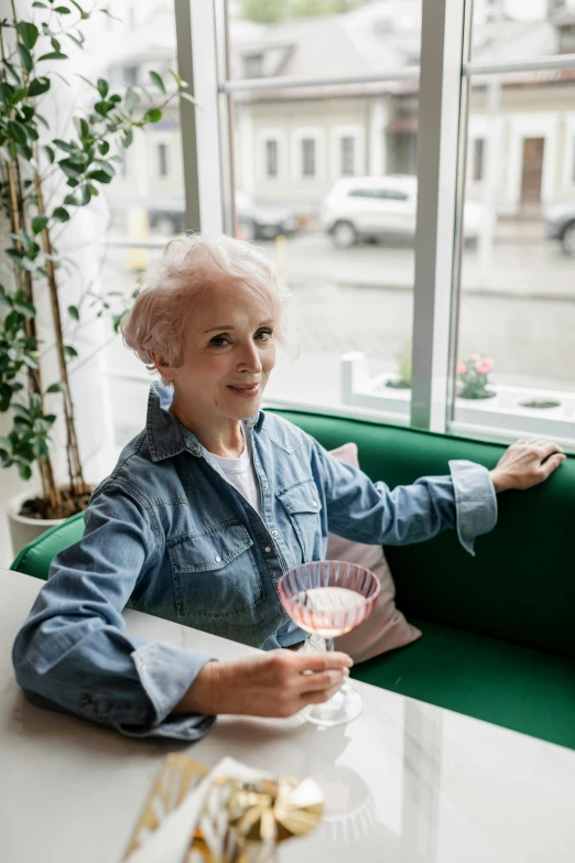 a woman sitting at a table with a glass of wine, white haired lady, wearing a shirt and a jean, 2019 trending photo, wearing a fancy jacket