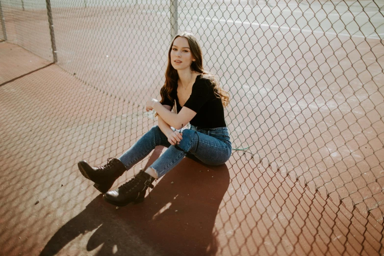 a woman sitting on the ground next to a fence, pexels contest winner, portrait sophie mudd, plain background, high school, ryan kiera armstrong