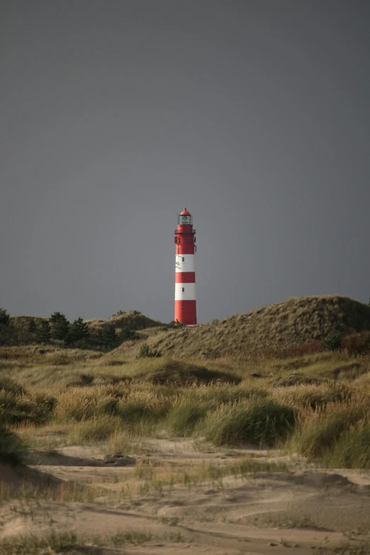 a red and white lighthouse sitting on top of a sandy beach, by Eglon van der Neer, square, moody, picture