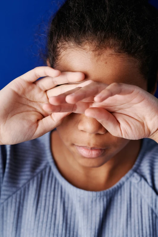 a woman covering her eyes with her hands, black teenage boy, slide show, partially cupping her hands, focused gaze