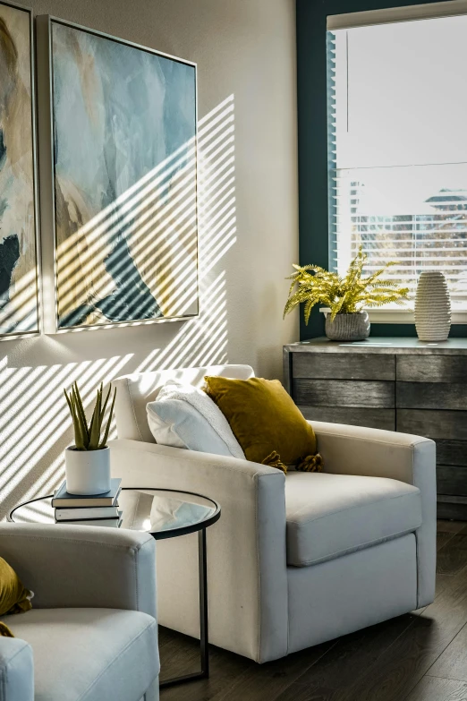 a living room filled with furniture and a large window, inspired by William Home Lizars, trending on unsplash, light and space, backlit golden hour, white and teal metallic accents, cozy arm chairs, soft light through blinds