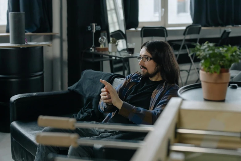 a man sitting on a couch using a cell phone, by Sebastian Spreng, pexels contest winner, arbeitsrat für kunst, ricky berwick, avatar image, in a open-space working space, kramskoi 4 k