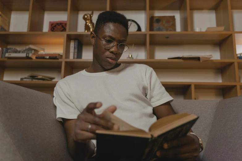 a man sitting on a couch reading a book, pexels contest winner, hyperrealism, man is with black skin, avatar image, studious, reading engineering book