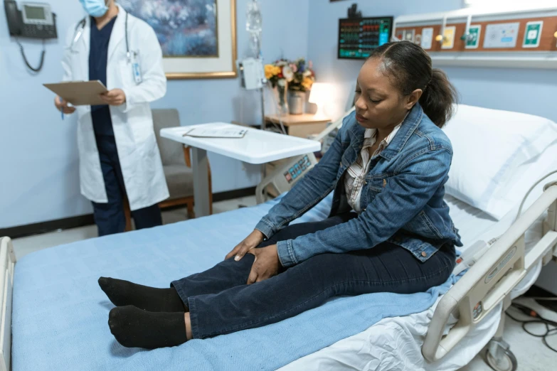 a woman sitting on a hospital bed next to a doctor, inspired by Dr. Atl, pexels contest winner, happening, shows a leg, j. h. williams iii, sitting on bent knees, cast