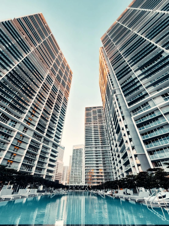 a large swimming pool surrounded by tall buildings, a screenshot, pexels contest winner, miami, three towers, up-close, luxurious environment