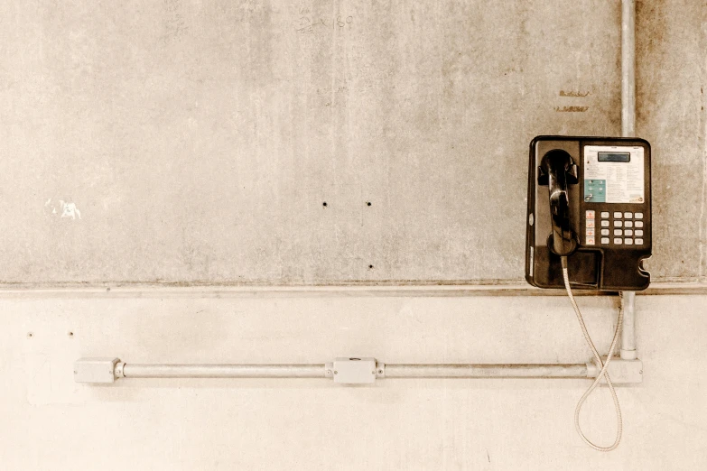 a telephone that is on the side of a wall, inspired by Elsa Bleda, unsplash, postminimalism, cables out of the ears, sepia, background image, in an underground parking garage