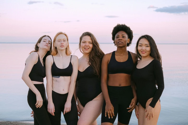 a group of women standing next to each other on a beach, inspired by Vanessa Beecroft, unsplash, renaissance, tight black tank top and shorts, skincare, (night), diverse