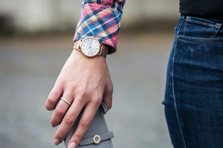 a close up of a person holding a wrist watch, inspired by Harrington Mann, happening, rose gold, holding a leather purse, multicoloured, wearing a flannel shirt