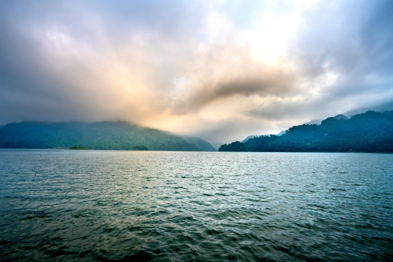 a large body of water with mountains in the background, an album cover, inspired by Tadao Ando, pexels contest winner, sumatraism, water mists, sri lankan landscape, lakeside, early evening