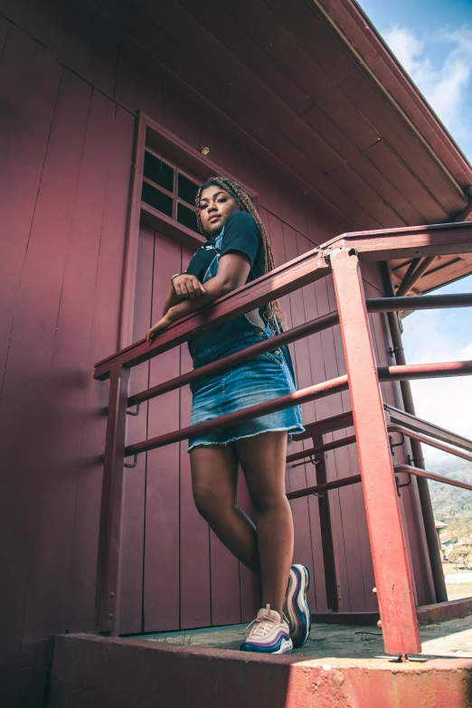 a woman standing in front of a red building, by Stokely Webster, unsplash, wearing shorts and t shirt, in a cabin, black teenage girl, hollister ranch