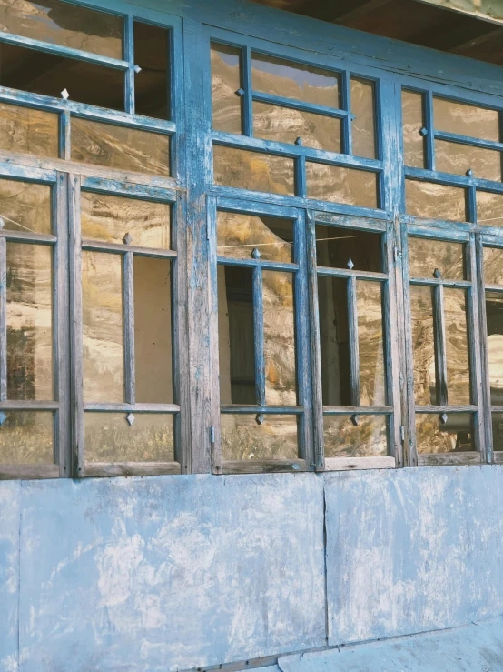 a man riding a skateboard down a sidewalk next to a building, an album cover, trending on unsplash, old town mardin, seen through broken glass, ((blue)), windows and walls :5