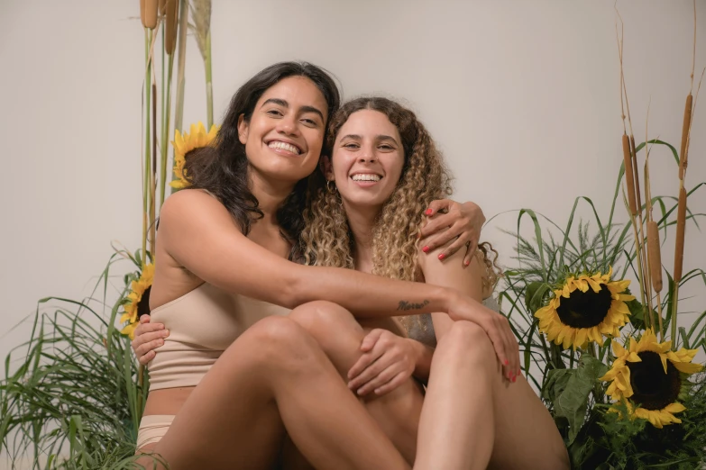 a couple of women sitting next to each other, tan skin, holding intimately, happy vibes, press shot