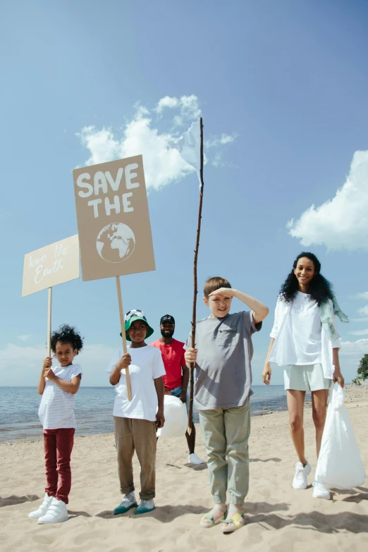 a group of people standing on top of a sandy beach, a colorized photo, pexels contest winner, environmental art, subject action: holding sign, kid, holding a spear, garbage